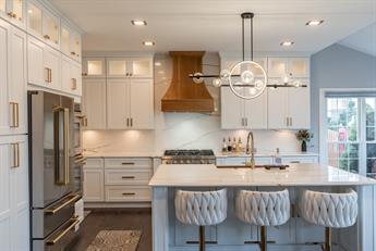 Kitchen with white shaker cabinets, glass-front uppers and a copper range hood