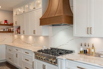 White shaker cabinets with a copper range hood and quartz countertops